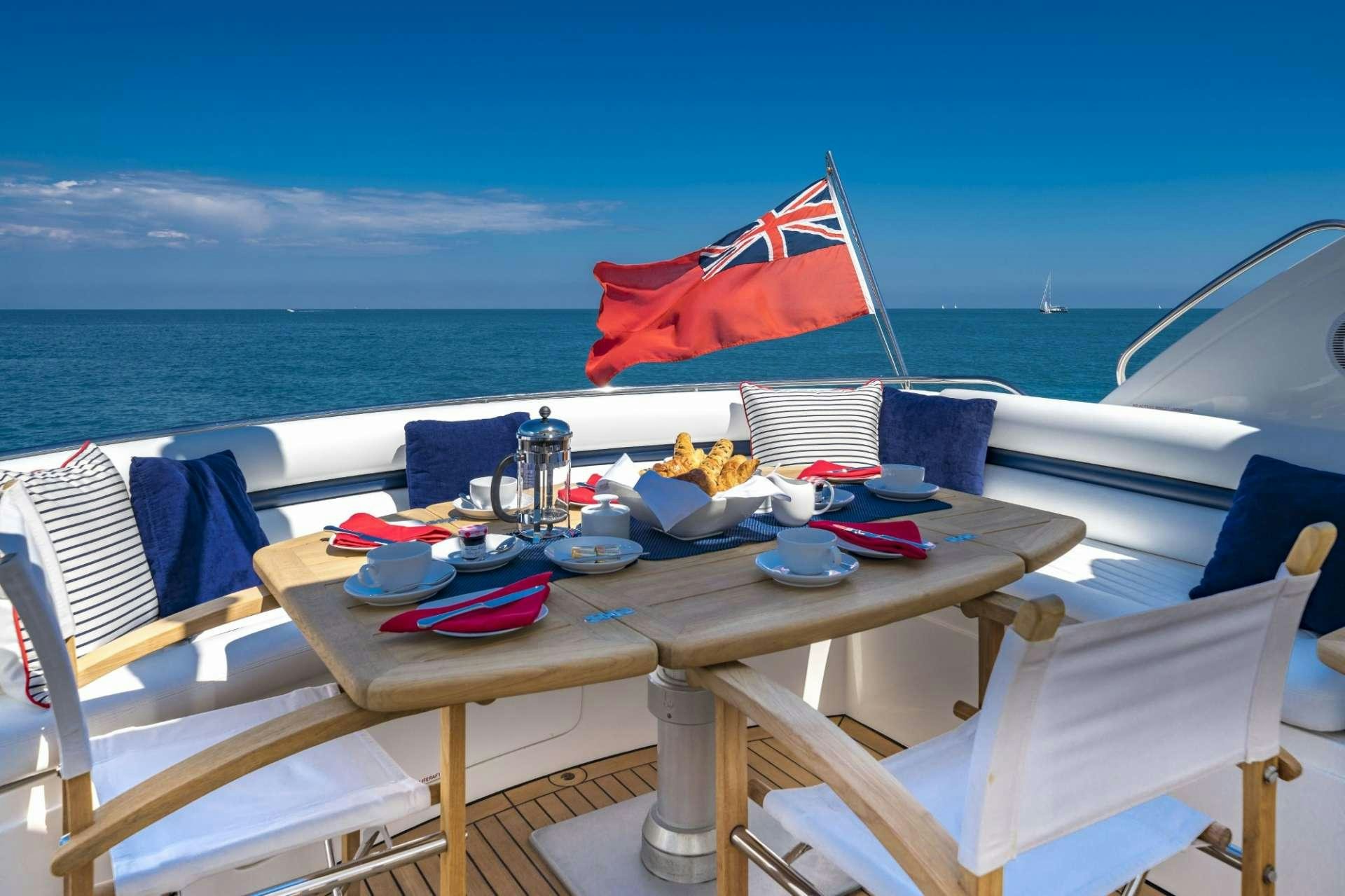 a table with food and drinks on it by the ocean aboard REHAB Yacht for Charter