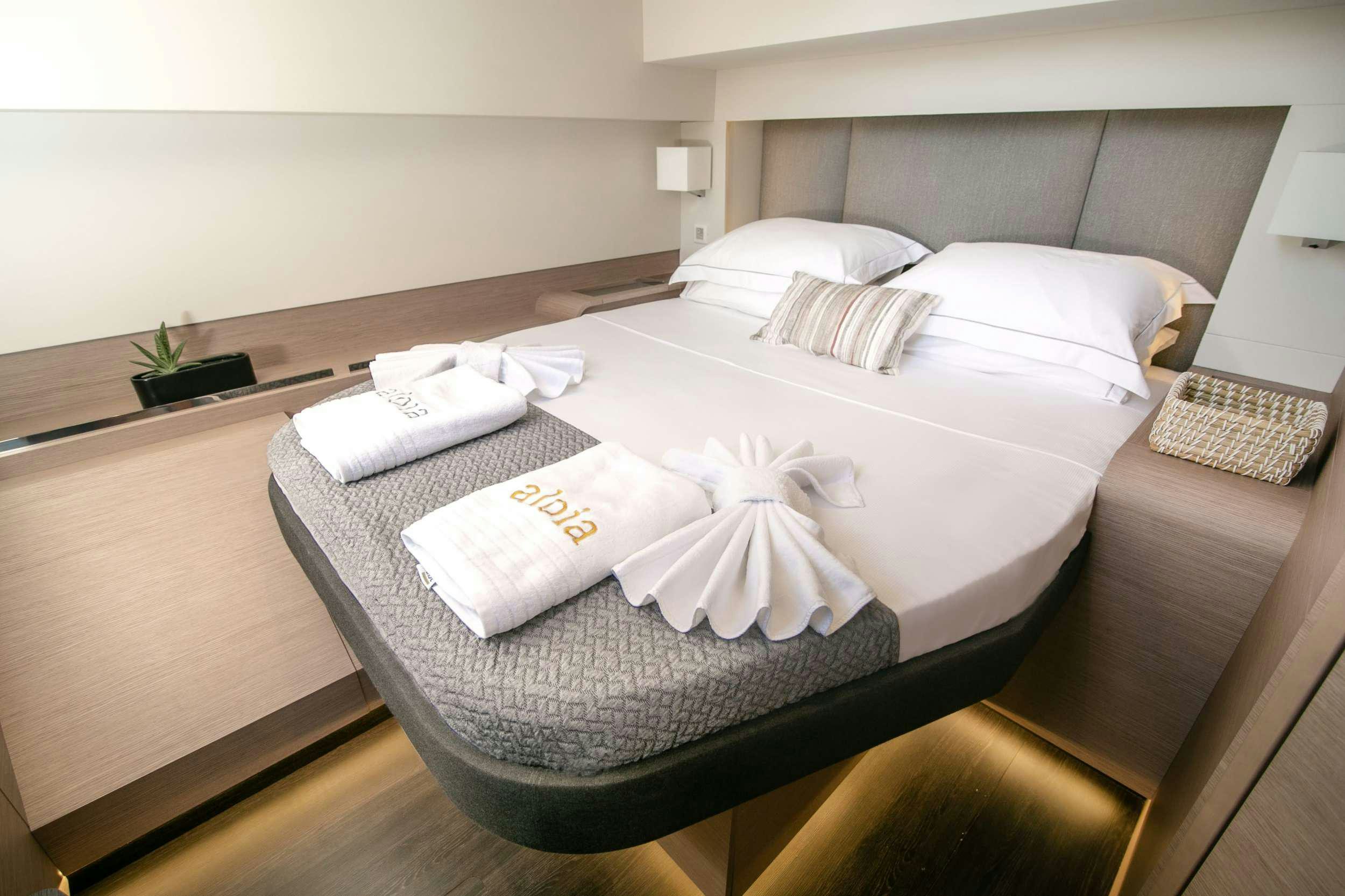 a bed with a white sheet and pillows on it aboard ALOIA  Yacht for Charter