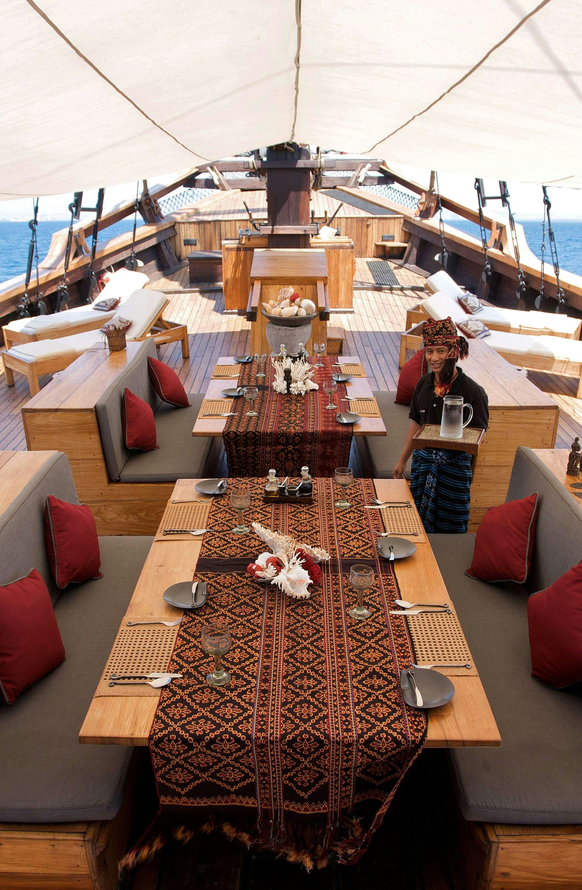 a person standing next to a table aboard SILOLONA Yacht for Charter