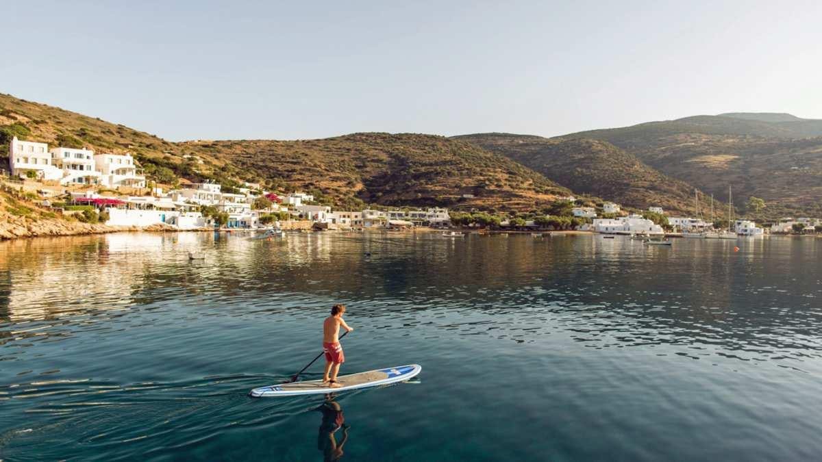 a couple of boys paddle on a surfboard in the water aboard KEPI Yacht for Charter