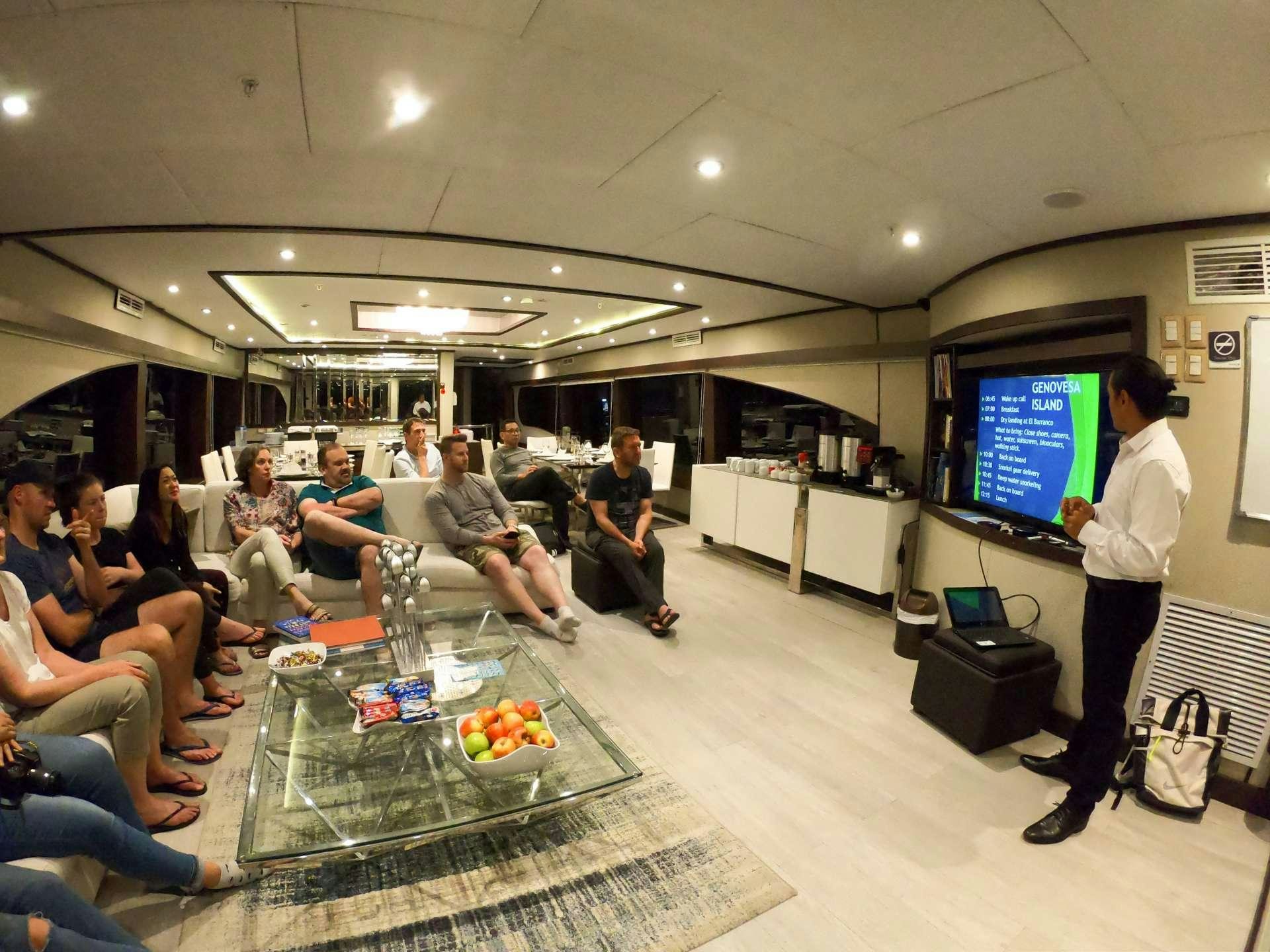 a group of people sitting in a room watching a person play a video game aboard GRAND MAJESTIC Yacht for Charter