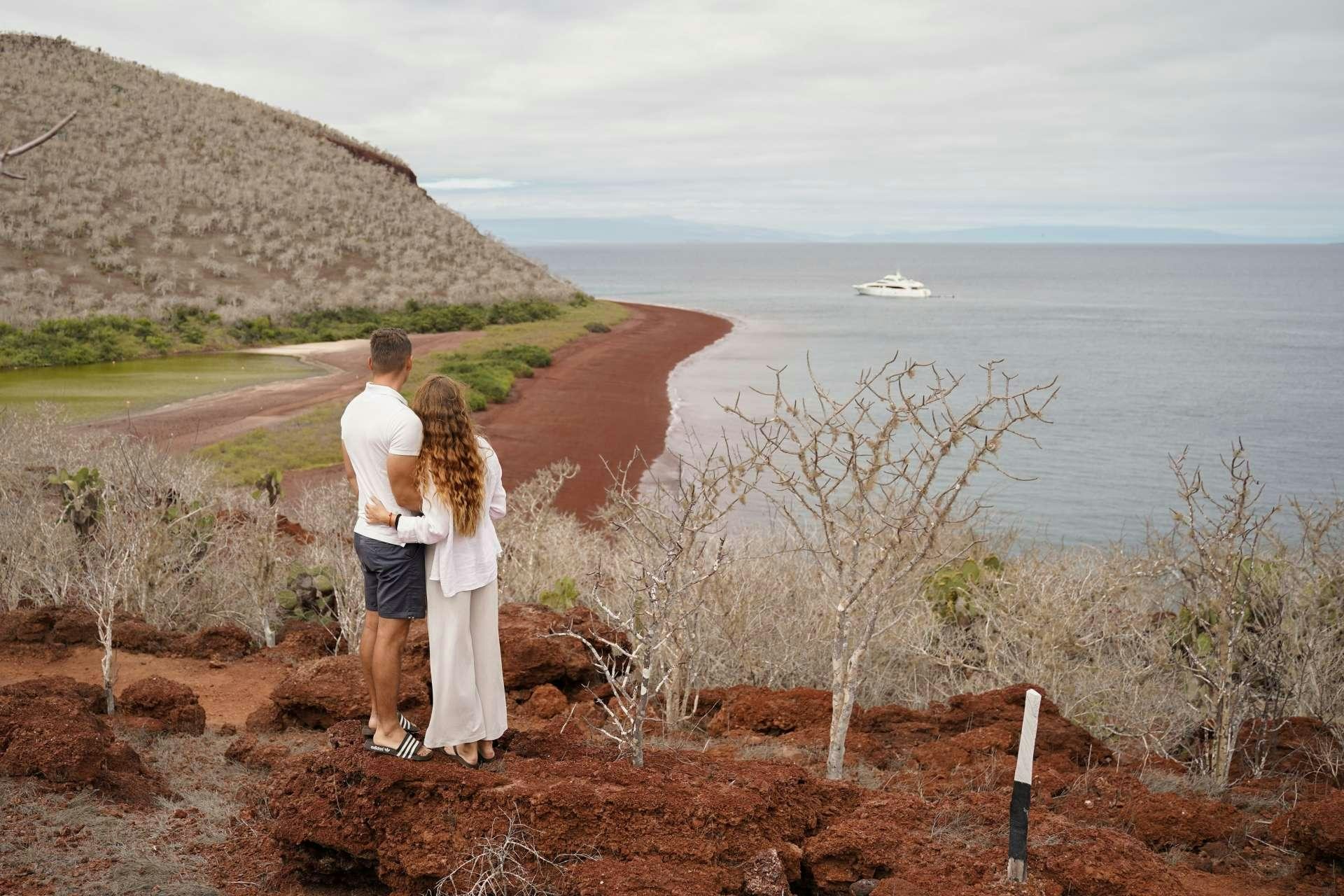 a man and woman kissing on a hill overlooking a lake aboard GRAND MAJESTIC Yacht for Charter