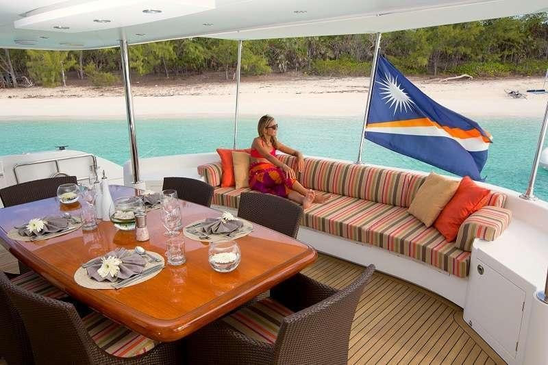 a couple sitting on a couch on a deck with a large blue and white striped umbrella aboard BLUE HORIZON Yacht for Charter