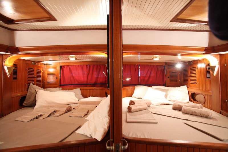 a room with beds and a red curtain aboard MORGANE Yacht for Charter