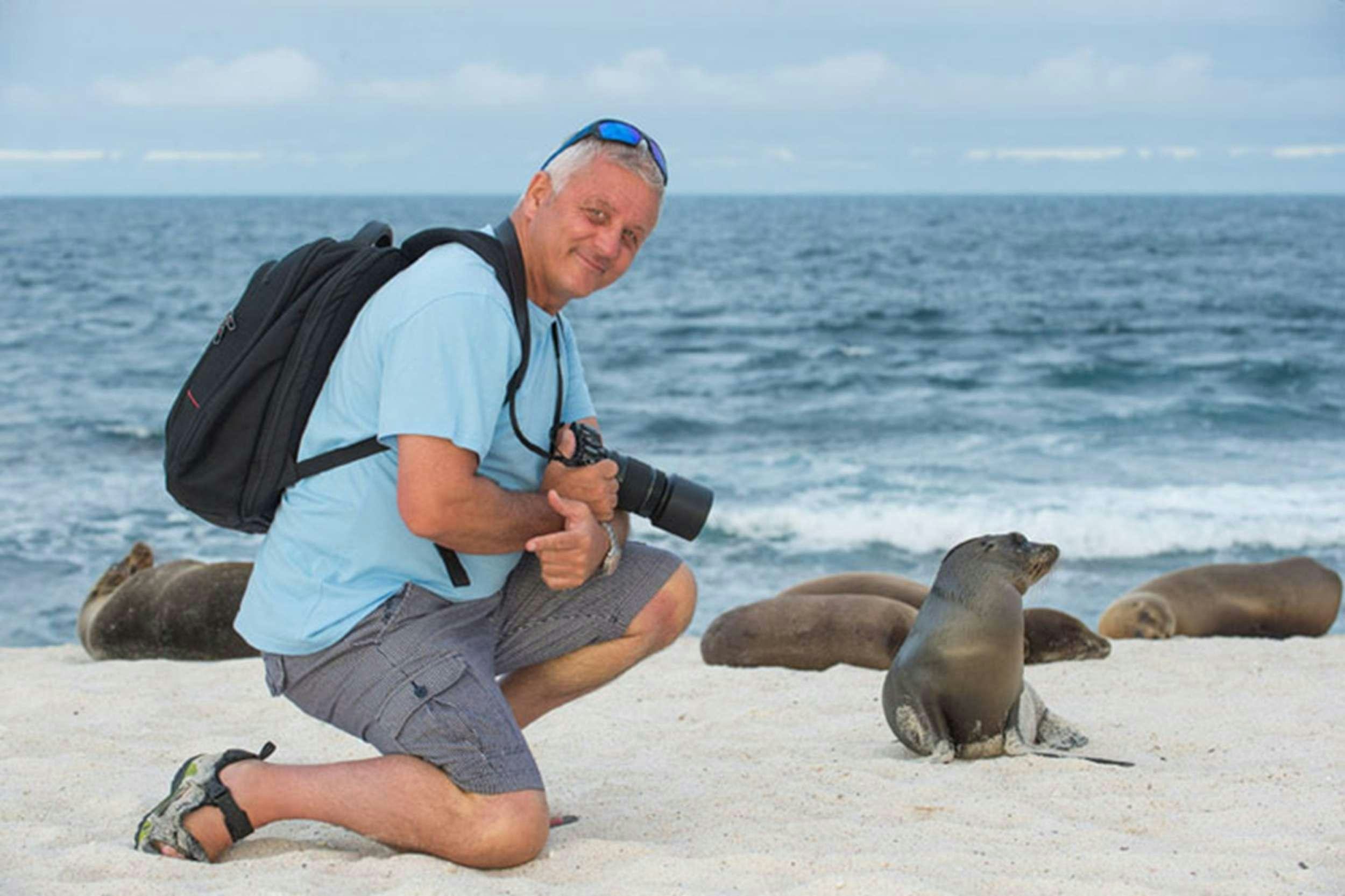a person kneeling on a beach with seals aboard NATURAL PARADISE Yacht for Charter