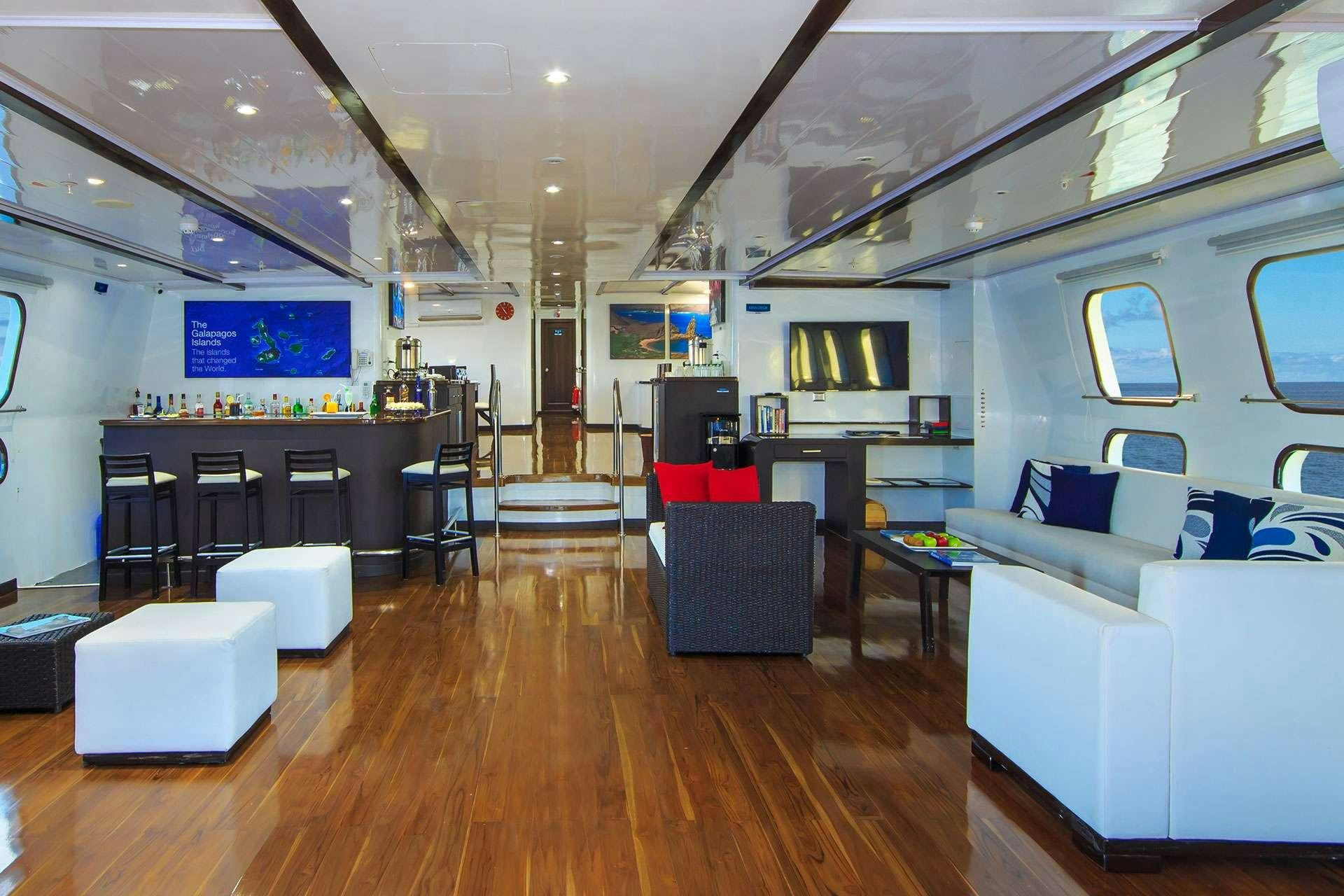 a room with a wood floor and white couches aboard NATURAL PARADISE Yacht for Charter