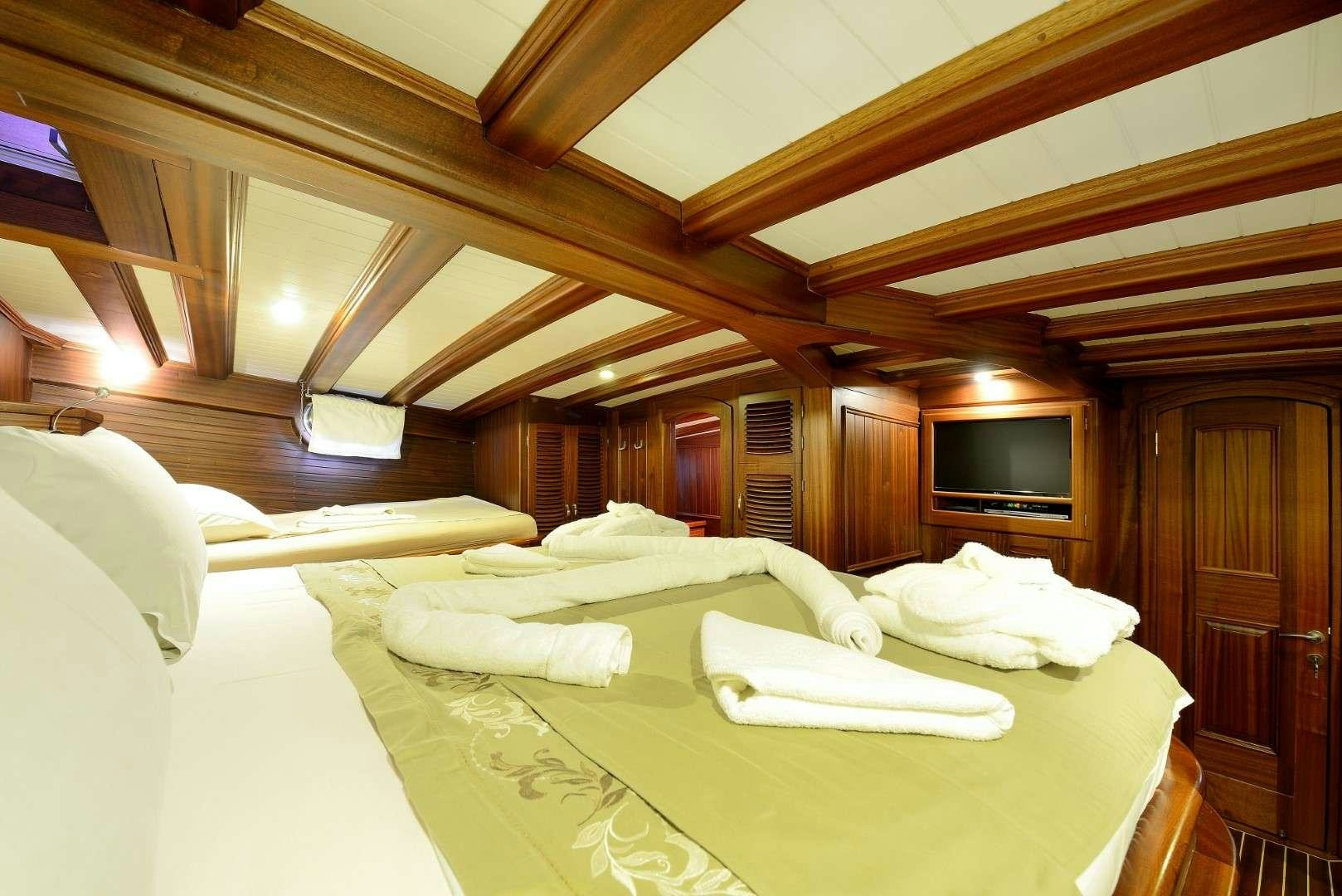 a room with a bed and a television aboard ZEPHYRIA II Yacht for Charter