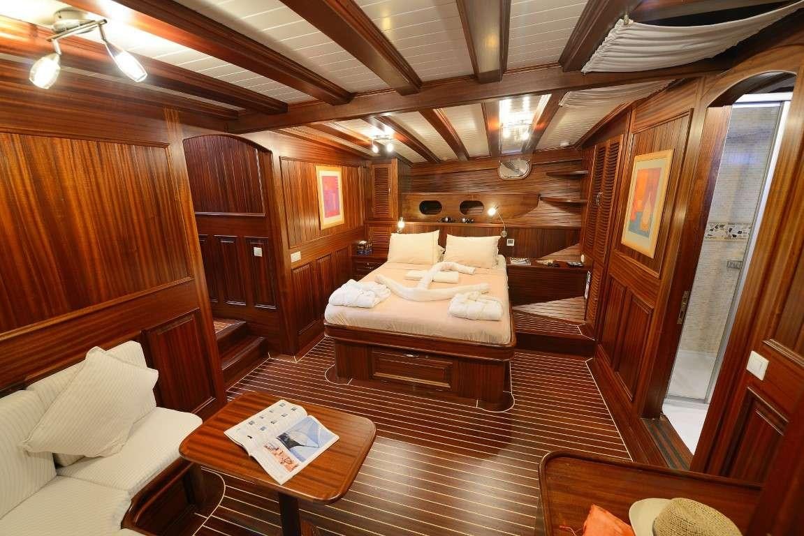 a room with a bed and a table aboard ZEPHYRIA II Yacht for Charter