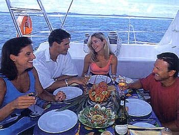 a group of people sitting at a table with food on it aboard CATALYST Yacht for Charter