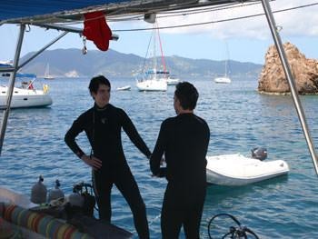 a couple of men in wet suits standing by a boat aboard CATALYST Yacht for Charter