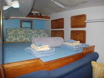 a bed with a blue sheet aboard CATALYST Yacht for Charter
