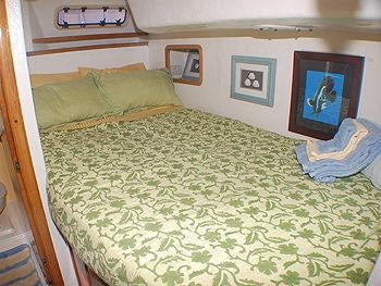 a bed with green sheets aboard CATALYST Yacht for Charter