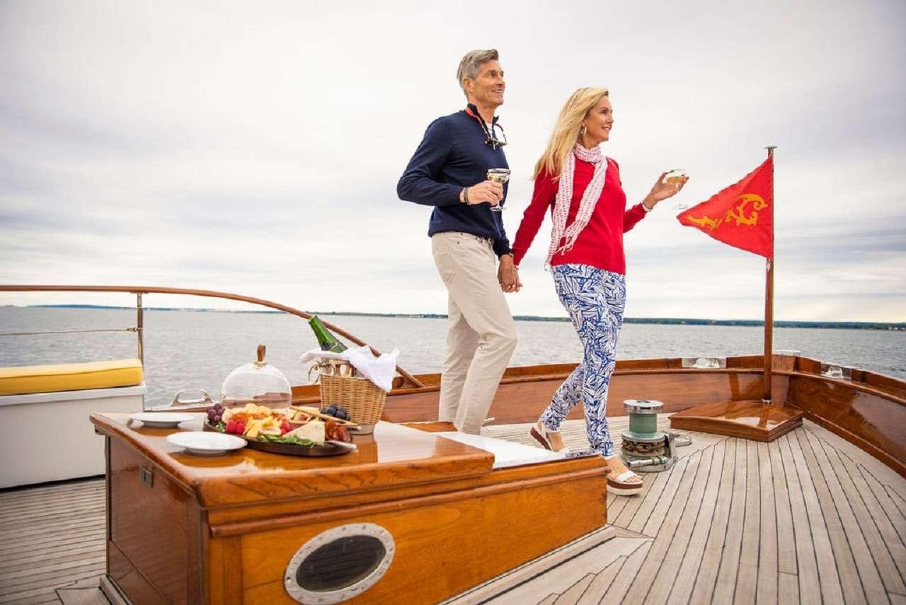 a man and woman standing on a dock with food and drinks aboard BB Yacht for Charter