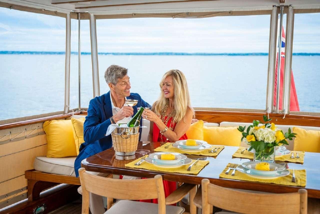 a man and woman sitting at a table with food and drinks aboard BB Yacht for Charter
