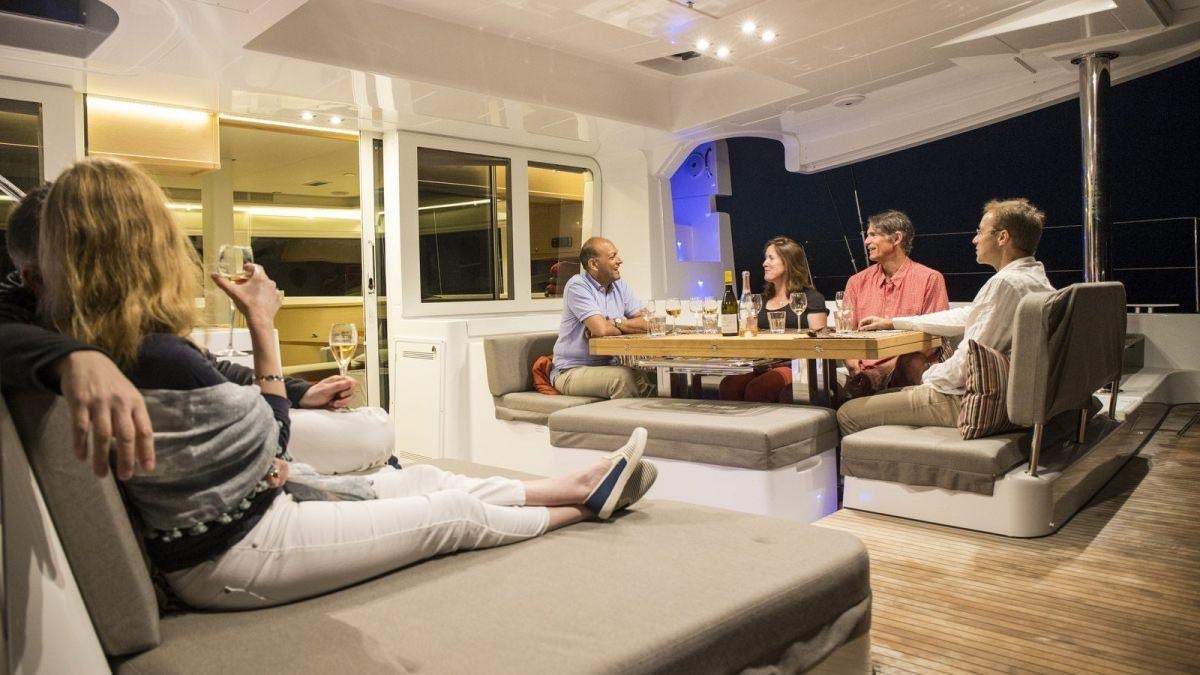 a group of people sitting around a table aboard LAGOON 52 Yacht for Charter