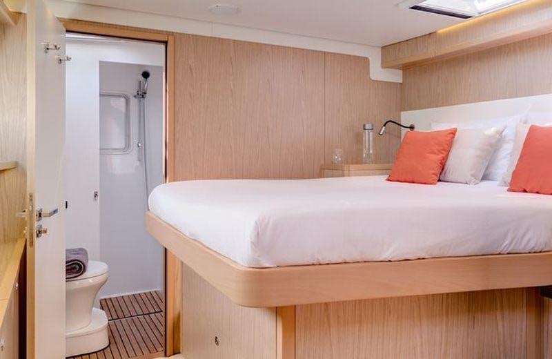 a bed with pink pillows aboard LAGOON 52 Yacht for Charter