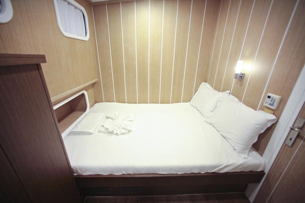 a bed with a white sheet and a lamp on it aboard OGUZBEY Yacht for Charter