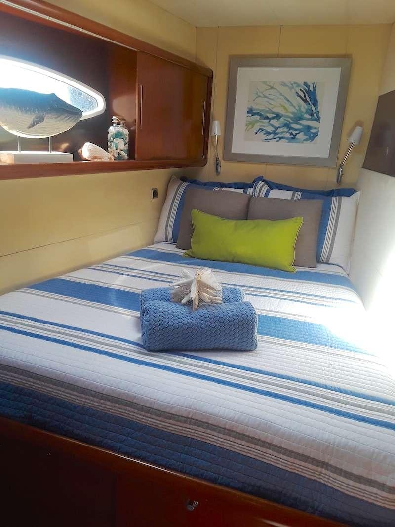 a bed with blue sheets aboard DELPHINE Yacht for Charter
