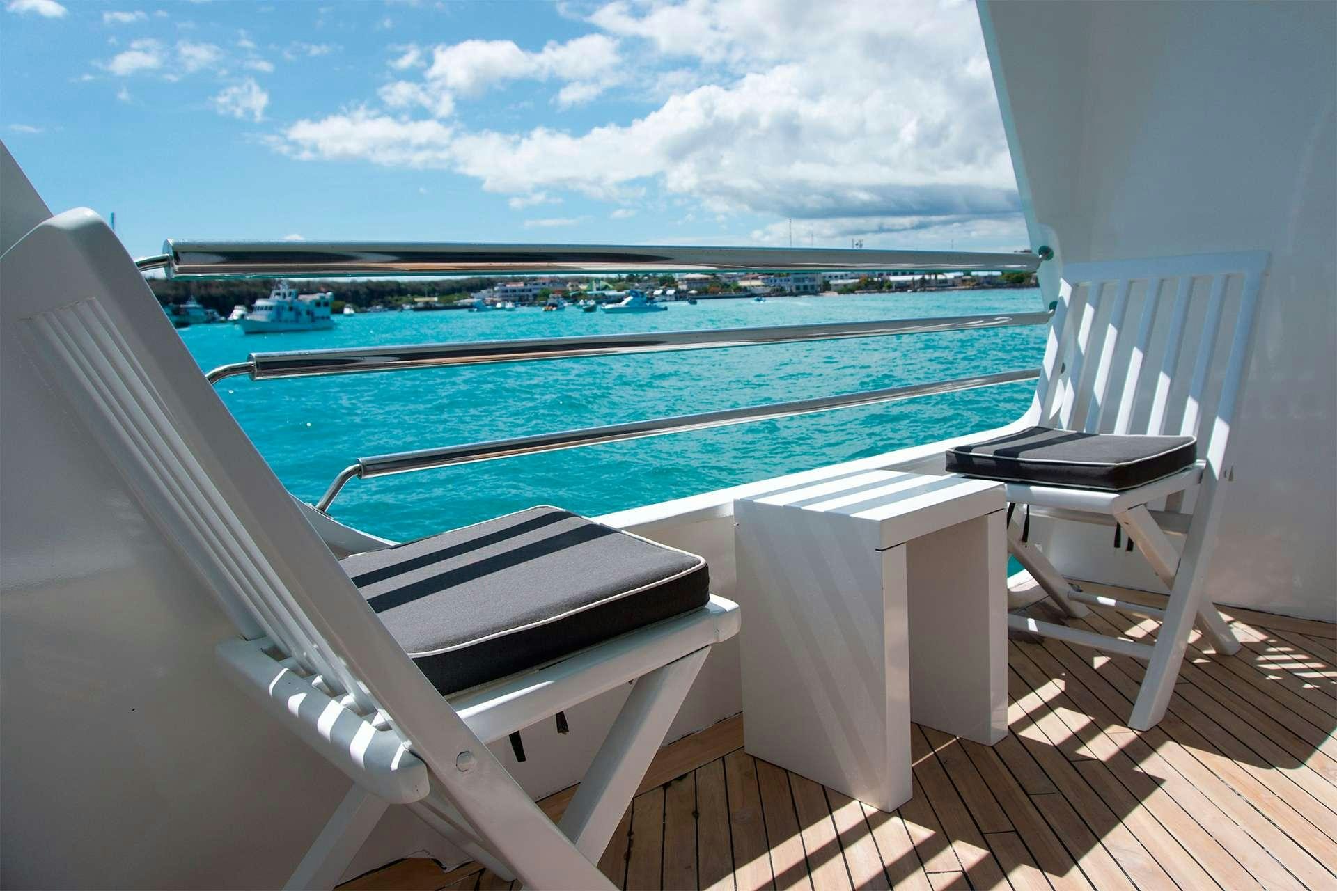 a deck with a chair and a pool and a view of the water aboard CORMORANT Yacht for Charter