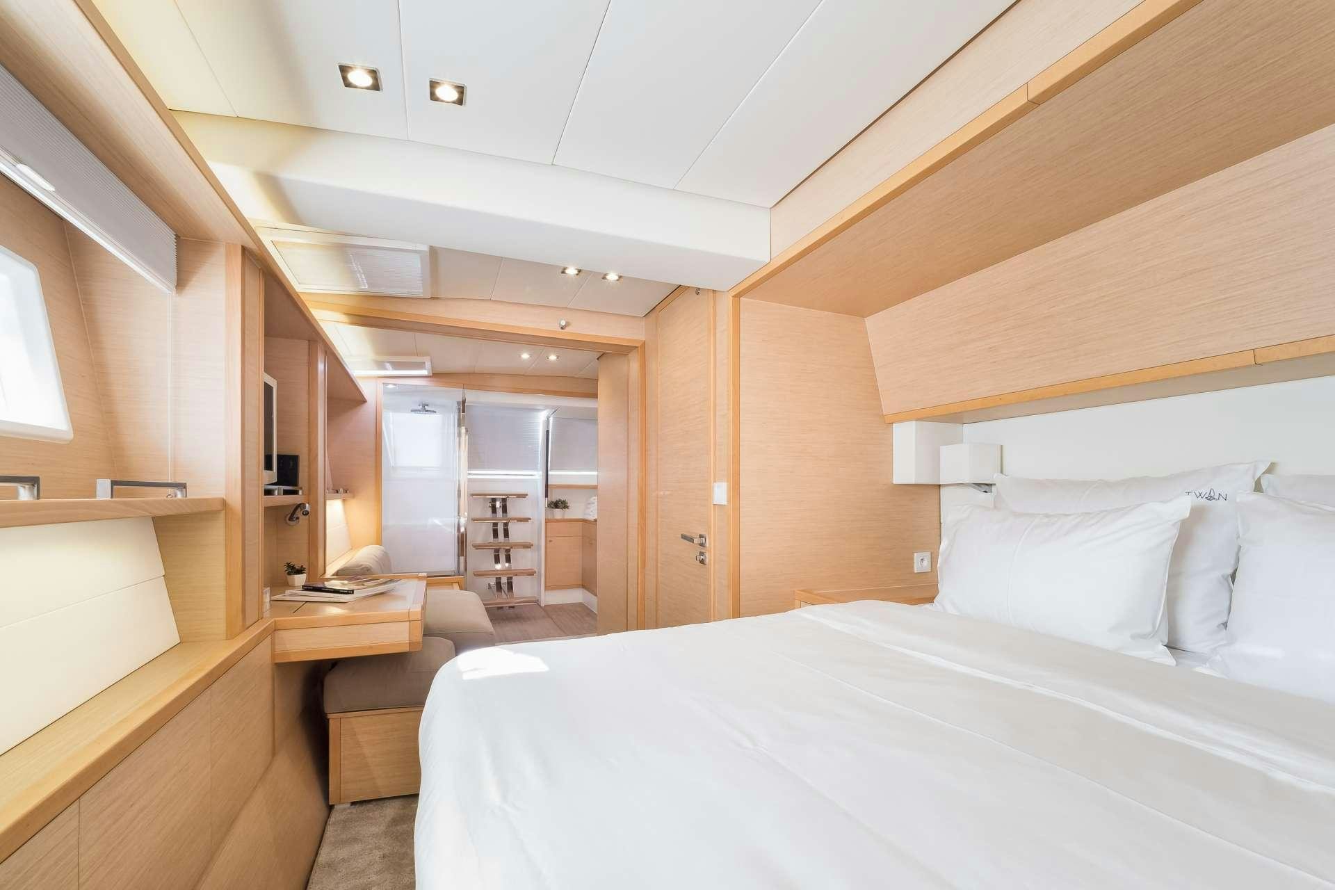 a room with a bed and a desk aboard TWIN Yacht for Charter