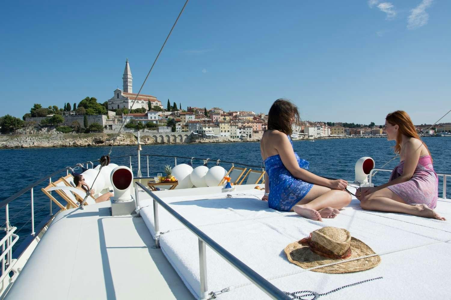a couple of women sitting on a boat looking at a sandwich aboard Play Fellow Yacht for Charter