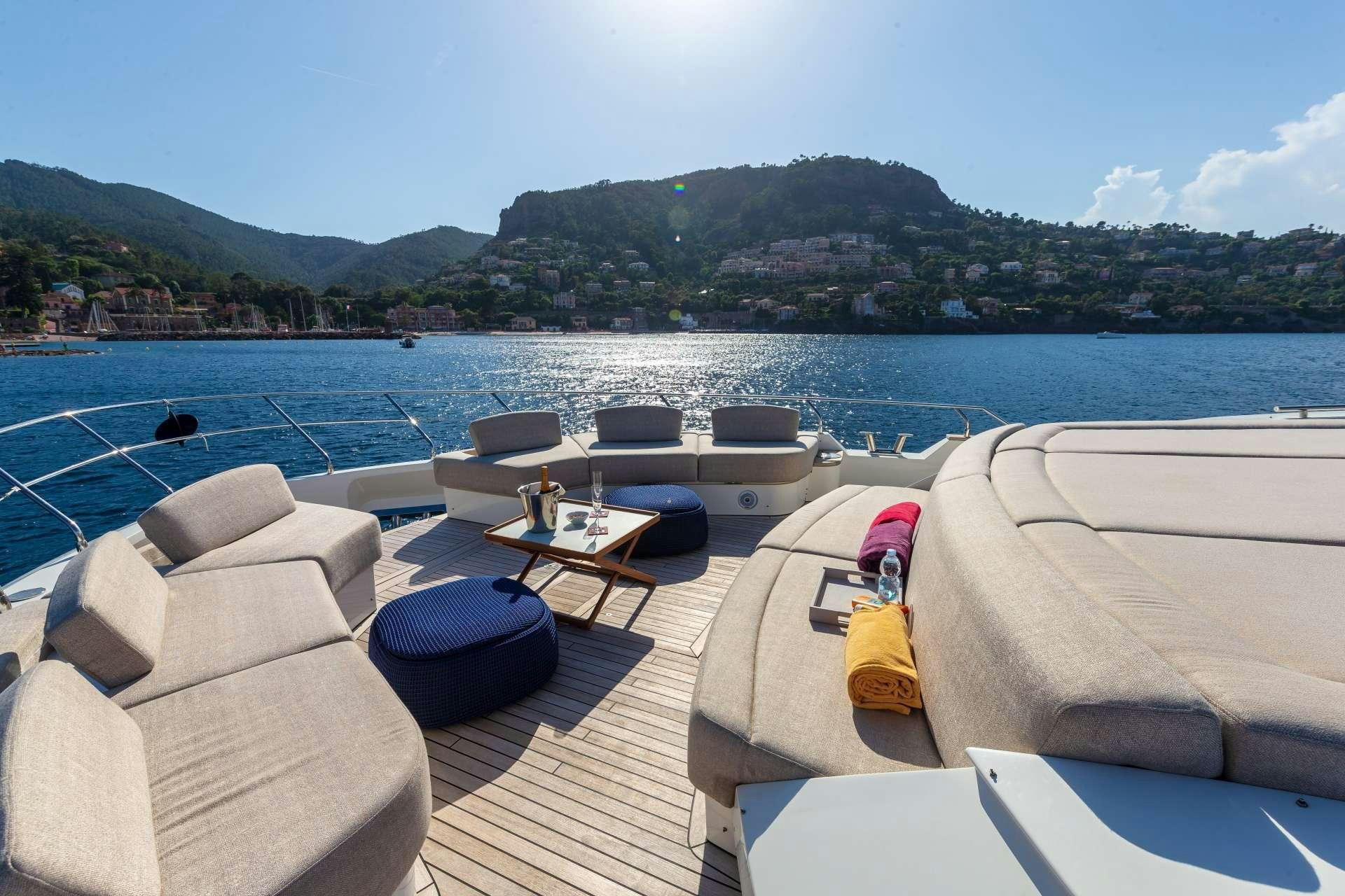 a deck with chairs and a table on it by a body of water aboard ESMERALDA OF THE SEAS Yacht for Charter
