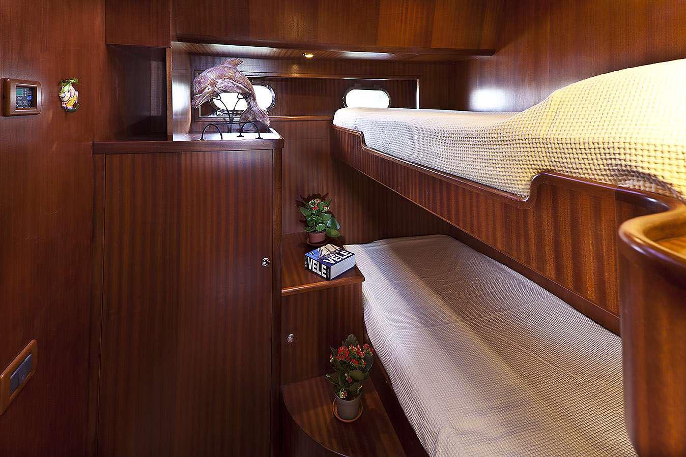a bed with a table and a plant in a room aboard MYOSOTIS Yacht for Charter