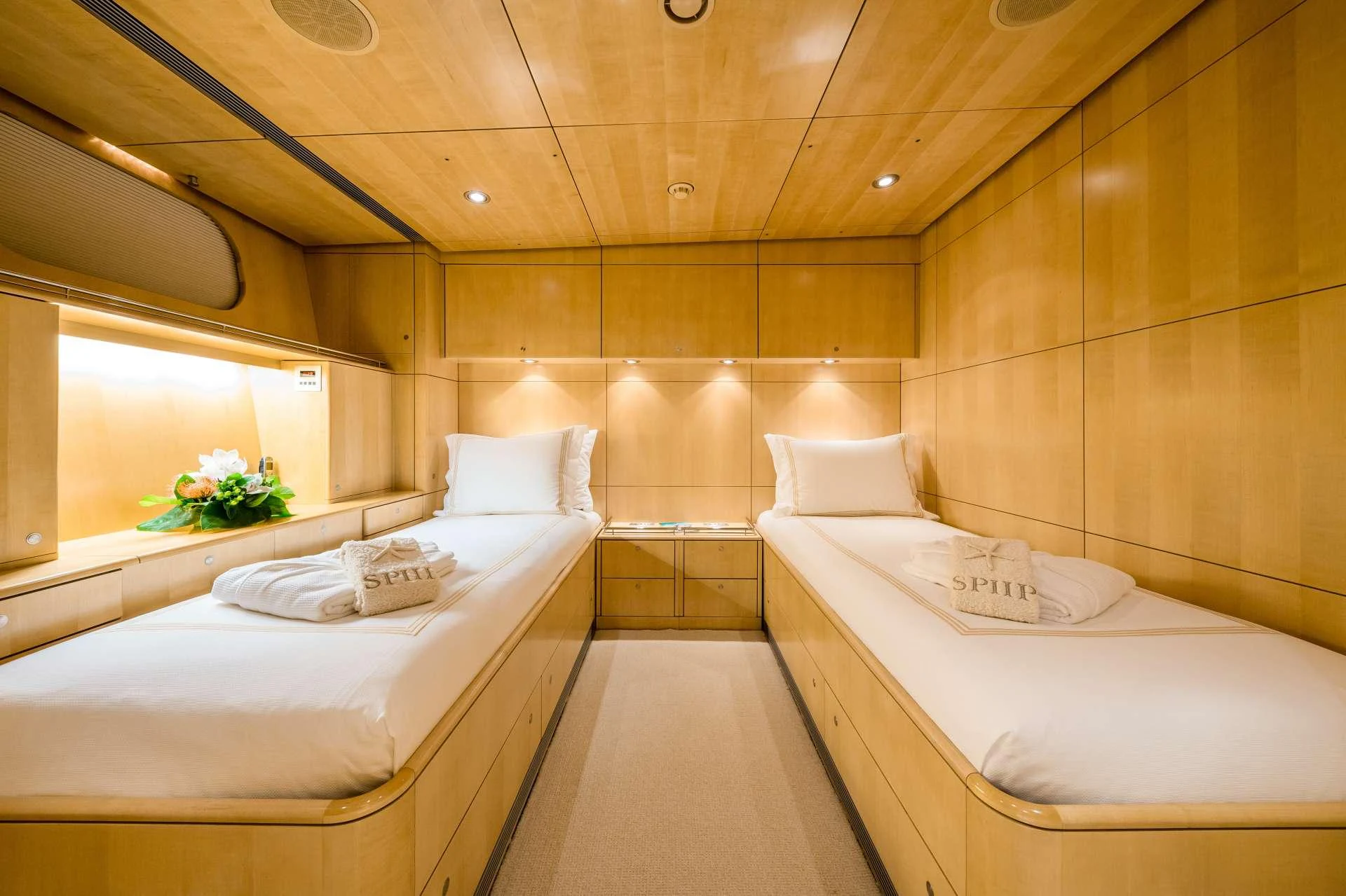 A cozy twin stateroom with warm wooden paneling and soft lighting. aboard SPIIP Yacht for Charter