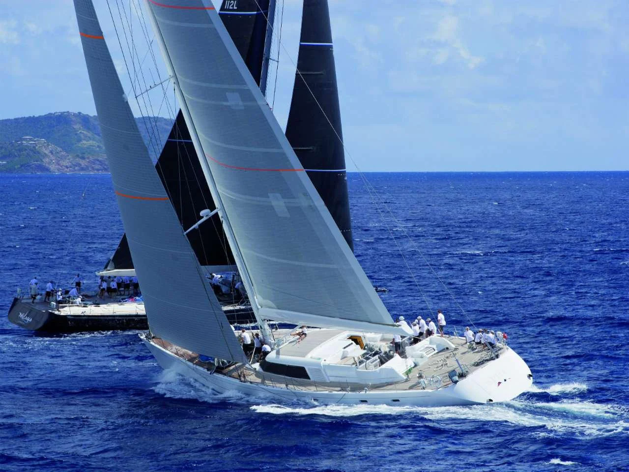 A sleek sailing yacht glides through the vibrant blue ocean waters under full sail. aboard SPIIP Yacht for Charter