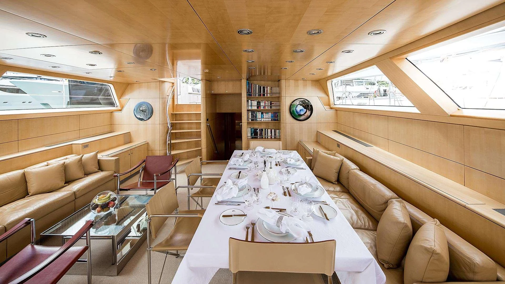 The yacht's dining area features a beautifully set table surrounded by plush seating and elegant wood paneling. aboard SPIIP Yacht for Charter