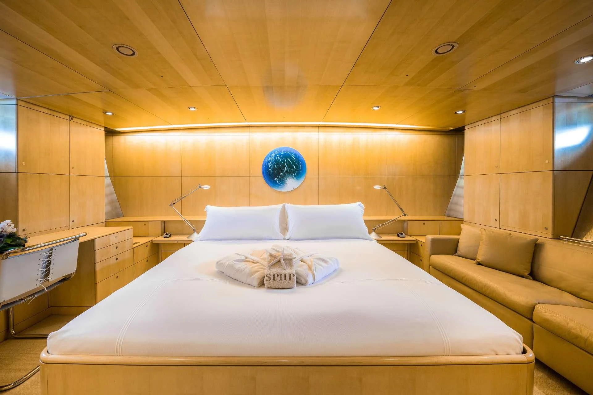 The master stateroom features a luxurious bed with elegant wooden paneling and ambient lighting. aboard SPIIP Yacht for Charter