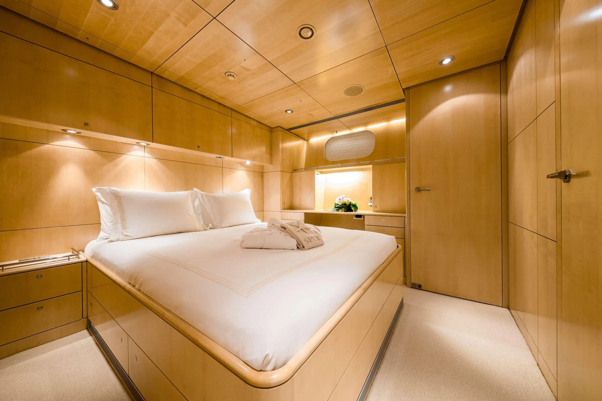 The stateroom features a luxurious bed with crisp white linens and warm wooden paneling. aboard SPIIP Yacht for Charter