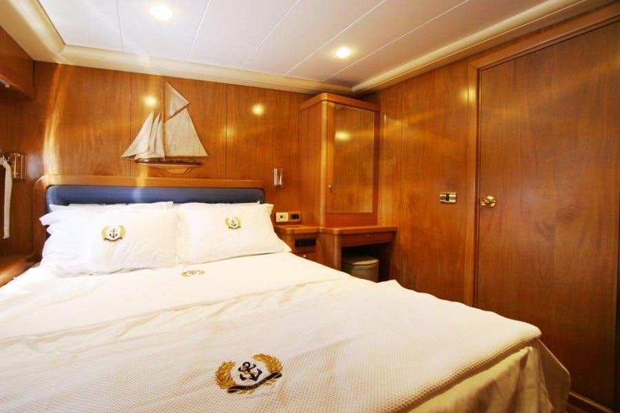 a bed with a white sheet and a wooden wall aboard MEIN SCHATZ Yacht for Charter