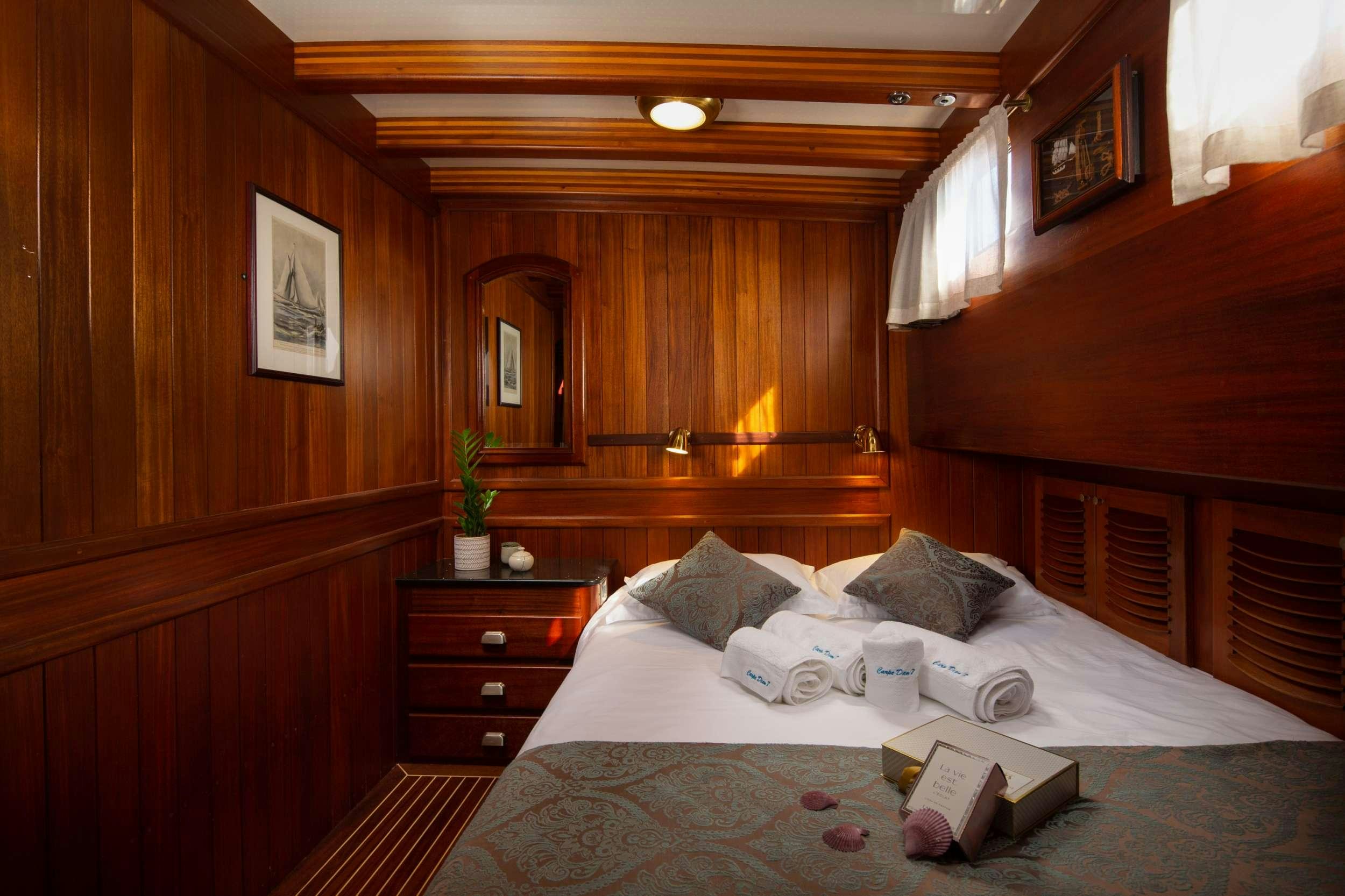 a bed with a white sheet and a wooden wall aboard Carpe Diem 7 Yacht for Charter