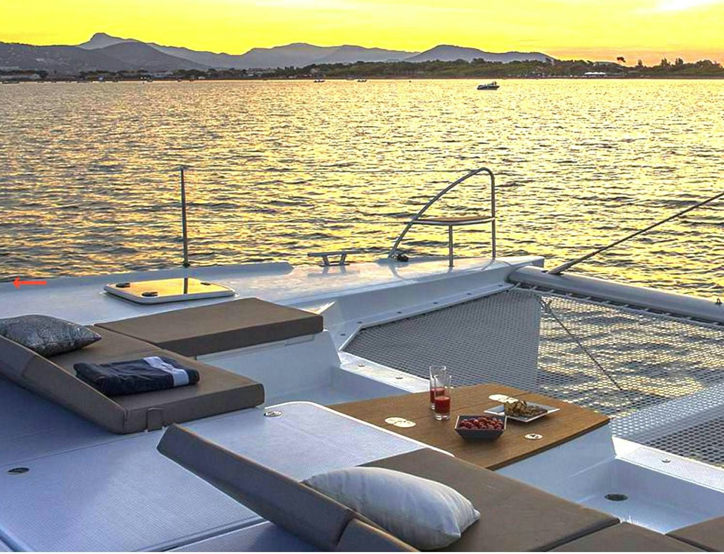 a deck with a table and a view of a sunset aboard MARIANN Yacht for Charter