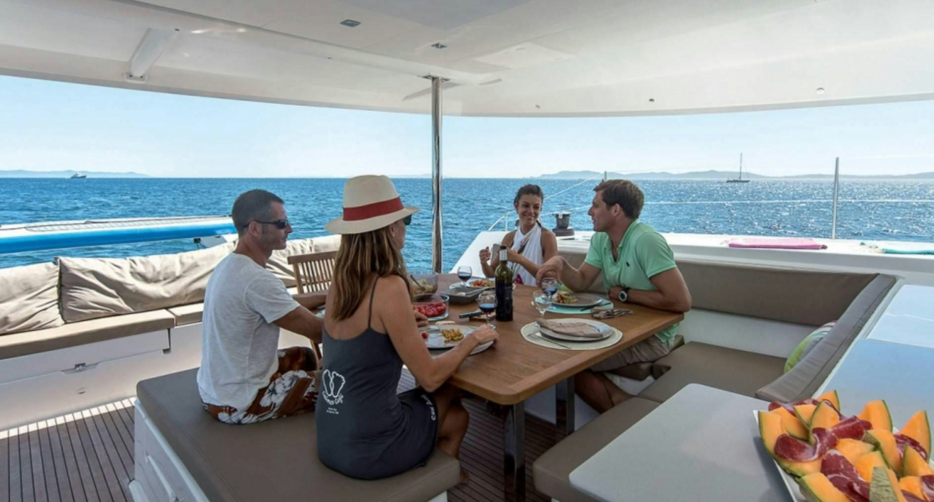 a group of people sitting at a table outside on a boat aboard MARIANN Yacht for Charter