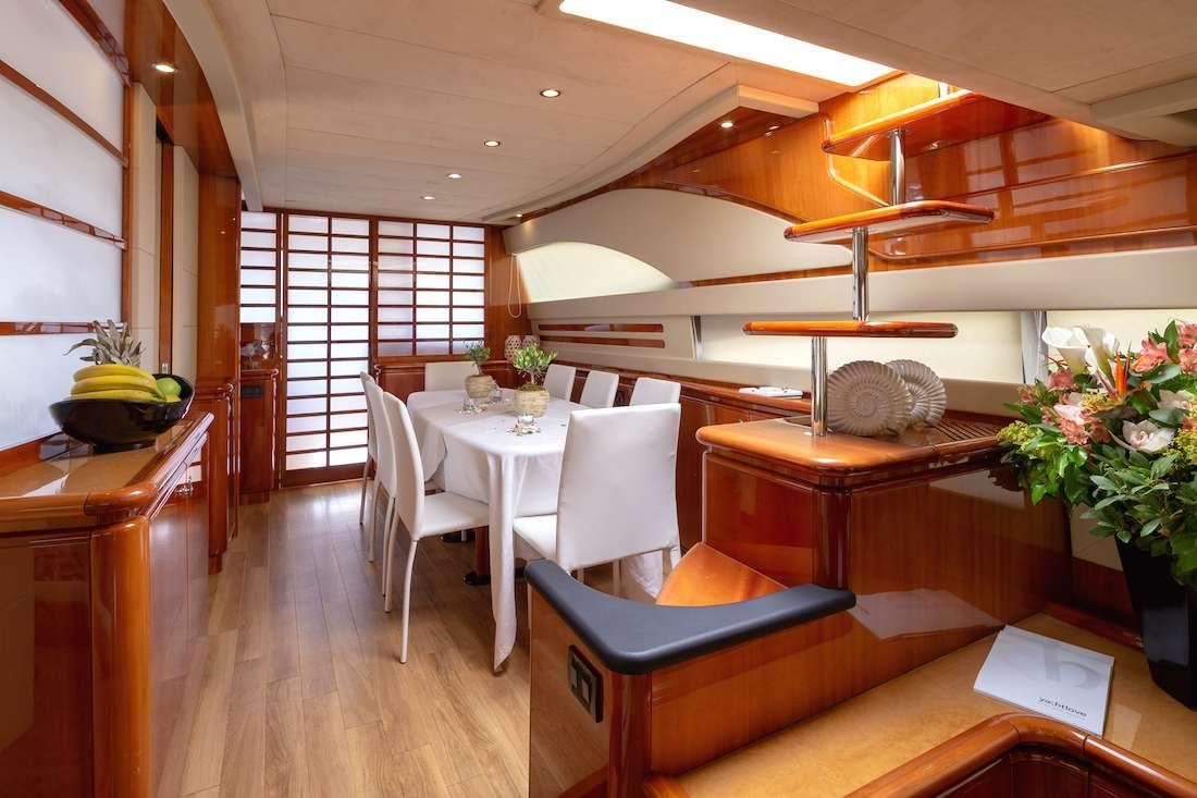a room with a table chairs and plants aboard AMOR Yacht for Charter