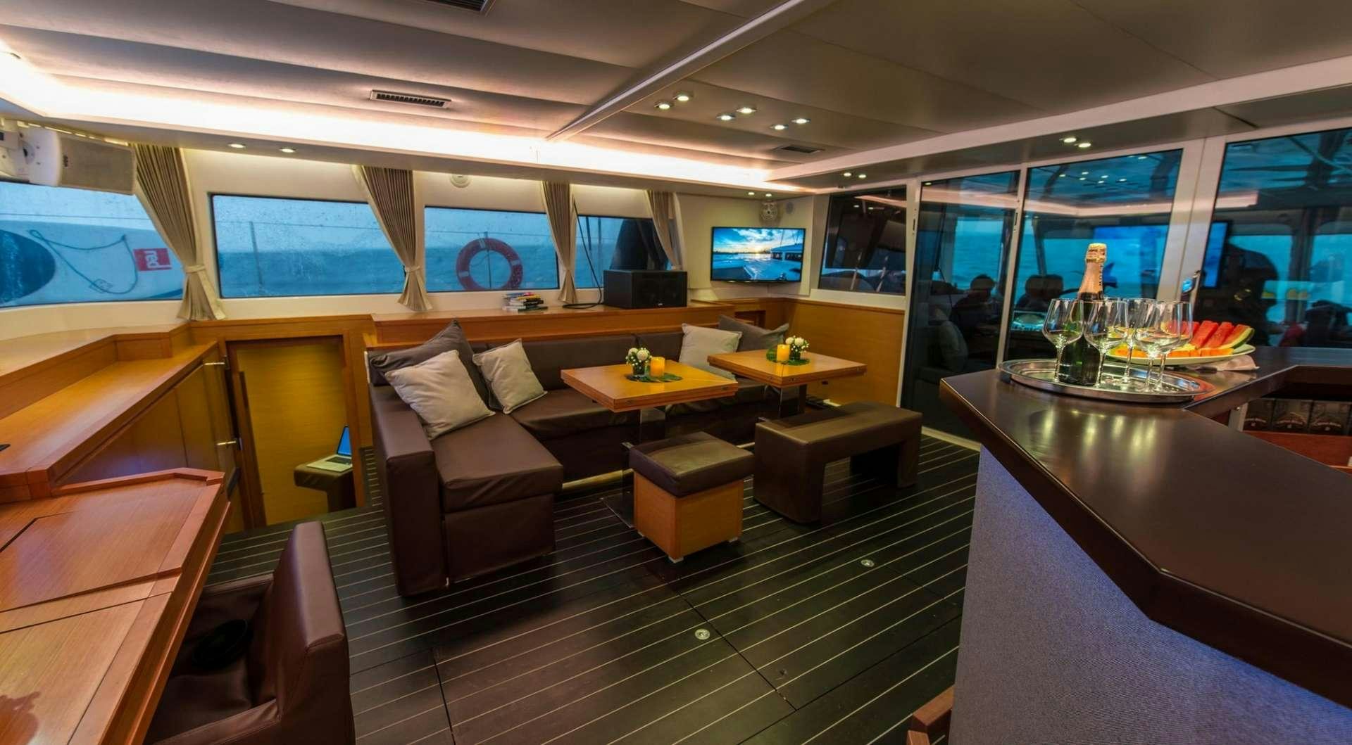 a room with a couch and a table with chairs and a tv aboard PRIMETIME Yacht for Charter