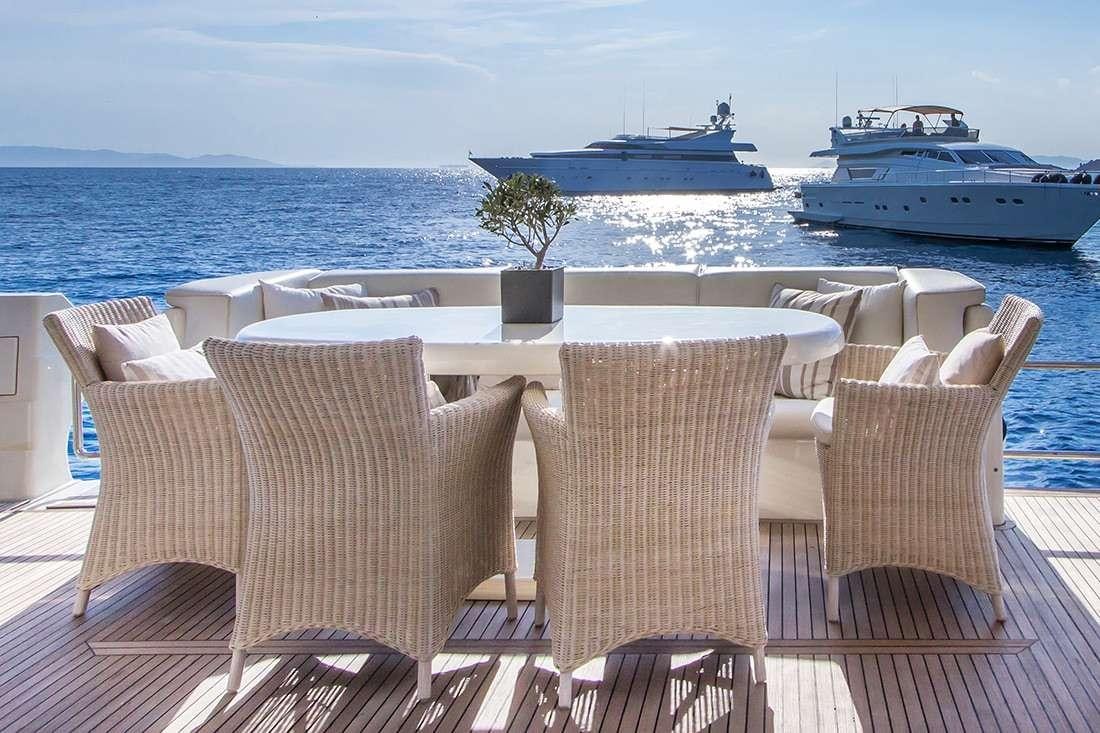 a table and chairs on a patio overlooking a large body of water aboard ROCK MOON Yacht for Charter