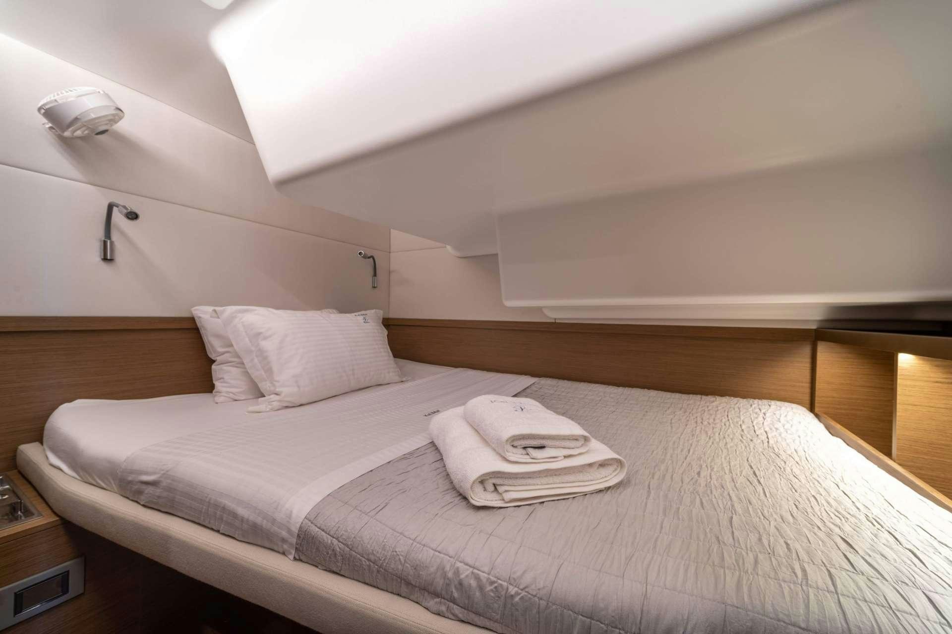 a bed with a white sheet on it aboard KaLiMar Yacht for Charter
