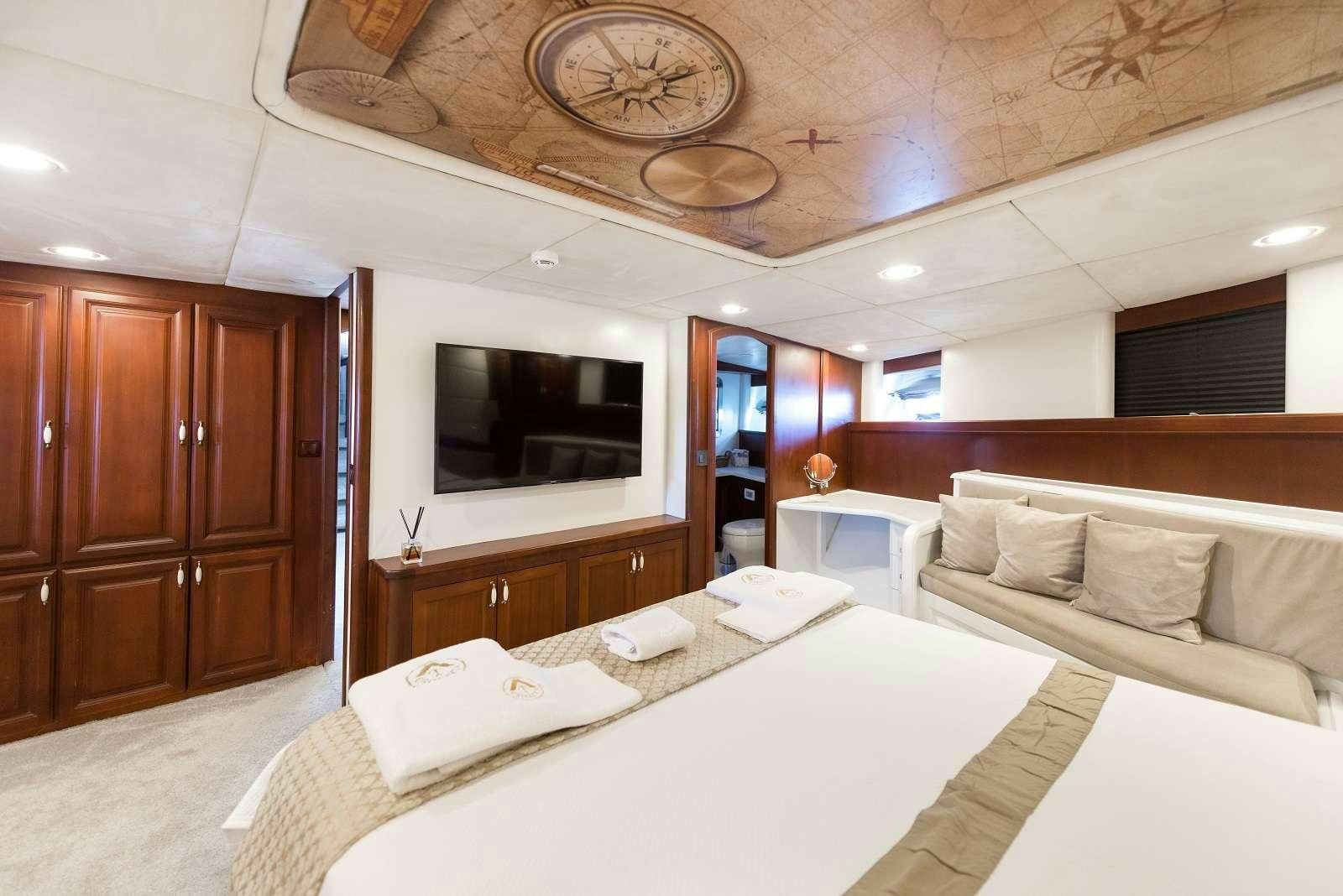 a room with a bed and a television aboard VIRTUOSO Yacht for Charter