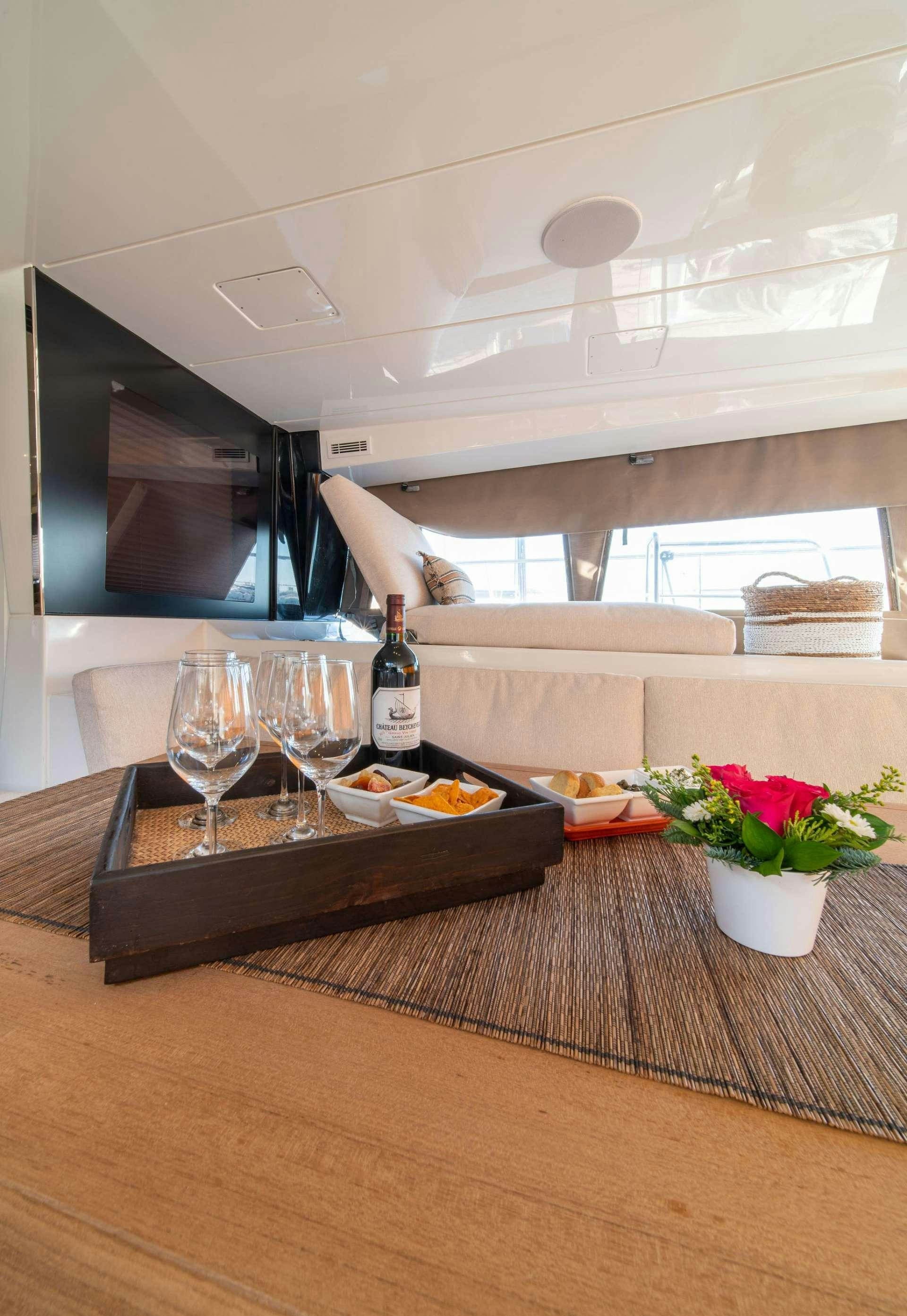 a person lying on a couch next to a table with food and wine aboard JUST MARIE Yacht for Charter