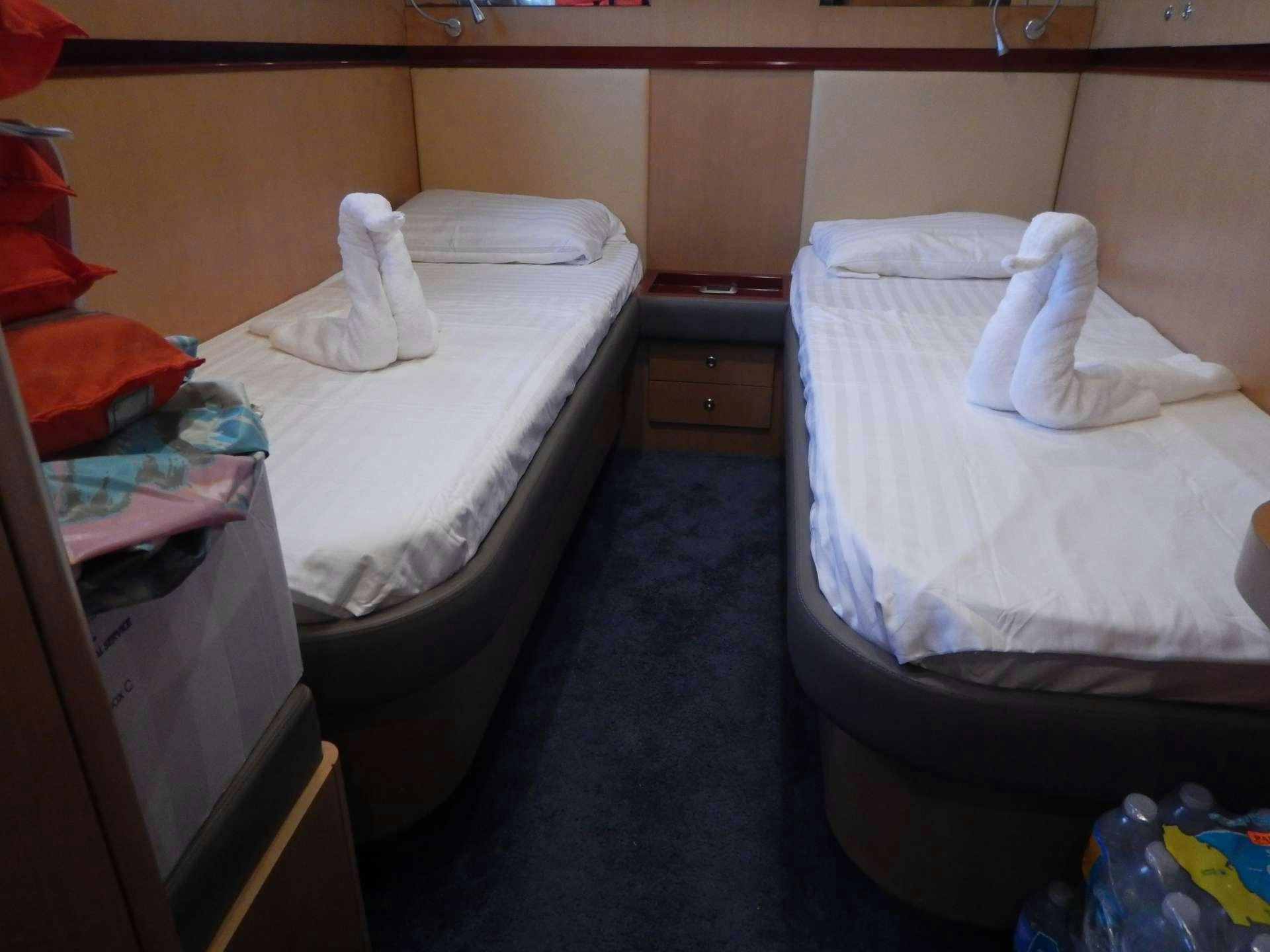 a room with beds and a dresser aboard MAGIC STAR Yacht for Charter