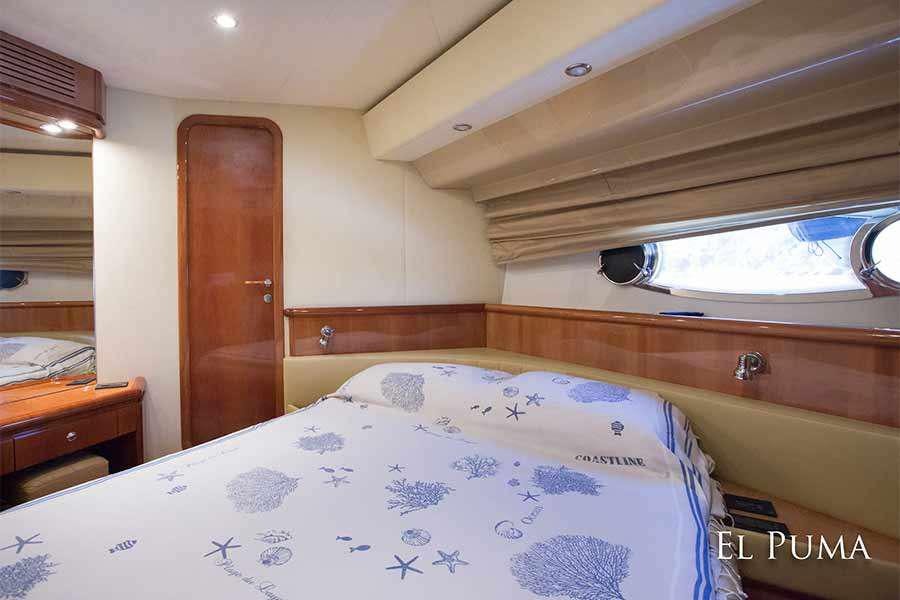 a bedroom with a bed and a wood door aboard EL PUMA Yacht for Charter