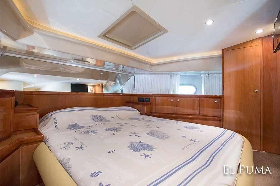 a bed with a white sheet and a wooden headboard aboard EL PUMA Yacht for Charter