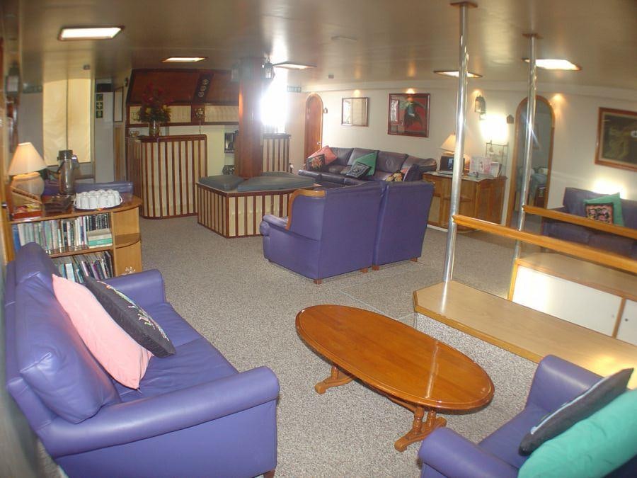 a living room with a blue couch and a table aboard CUAN LAW Yacht for Charter