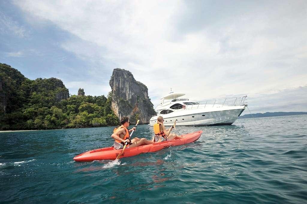 a couple people in a canoe in the water by a boat aboard LADY KATHRYN Yacht for Charter