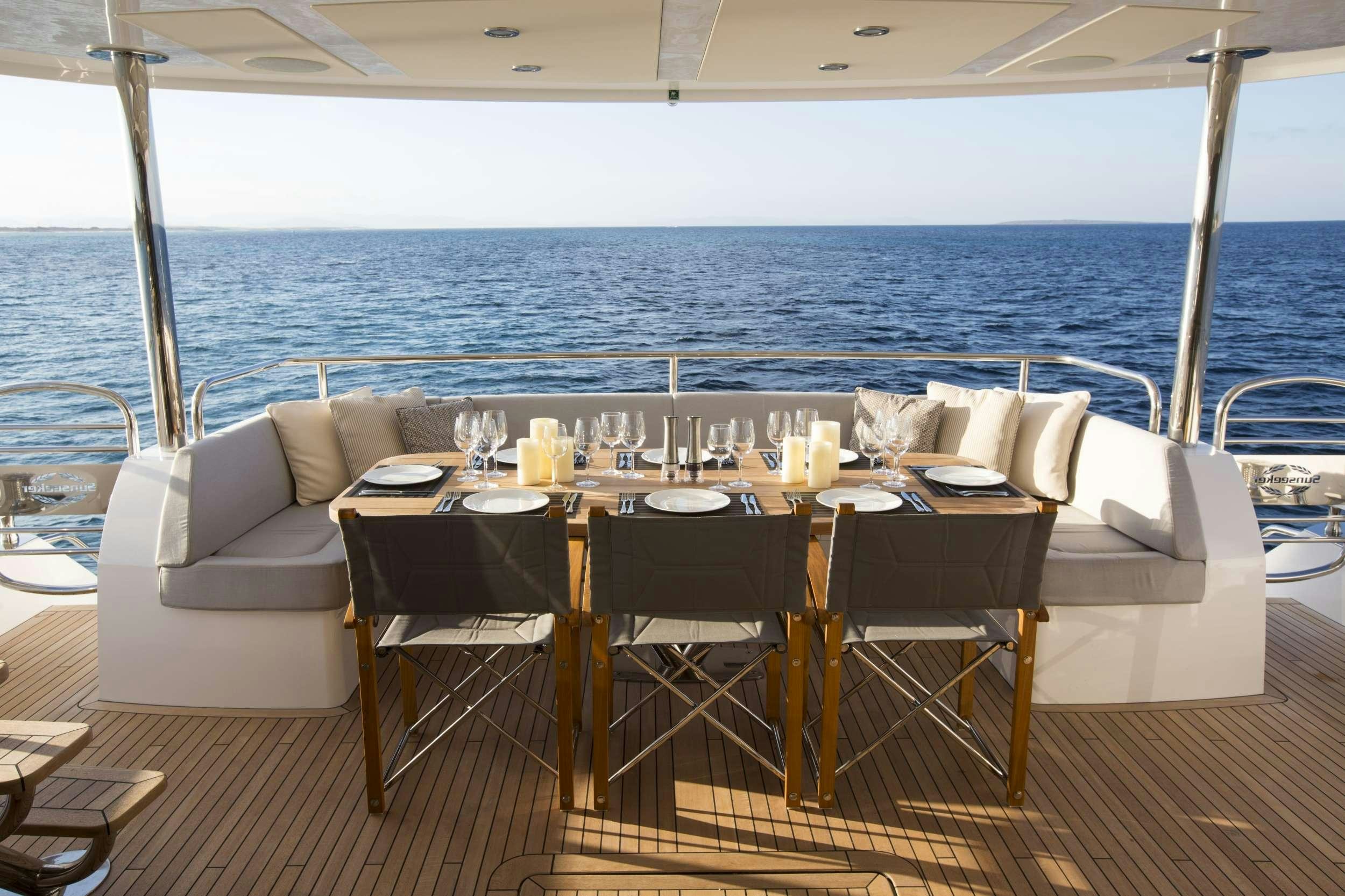 a table set for a meal on a deck overlooking the ocean aboard PLAY THE GAME Yacht for Charter