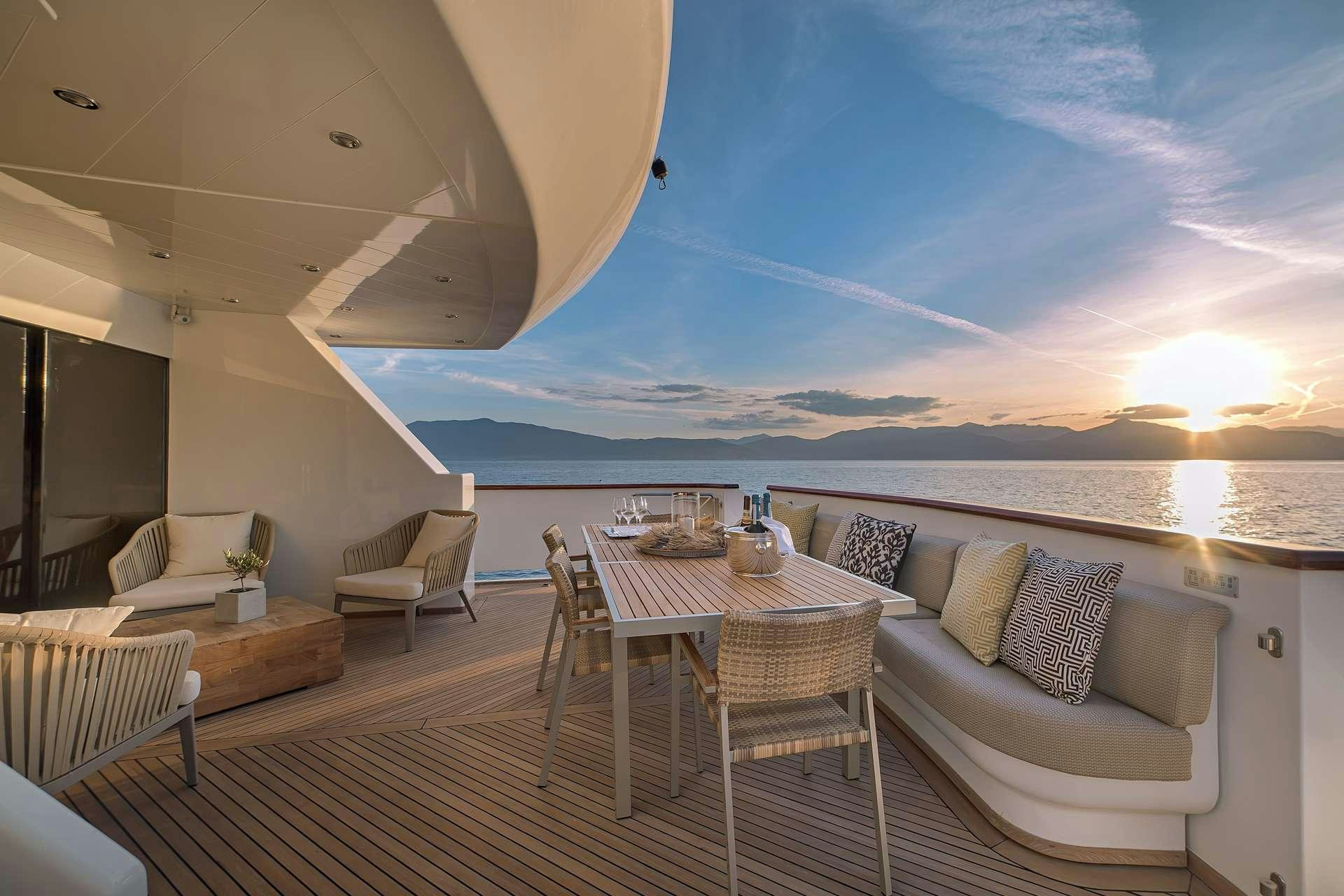 a large white lounge area with a large white sofa and a large white table with a white chair aboard AQUILA Yacht for Charter