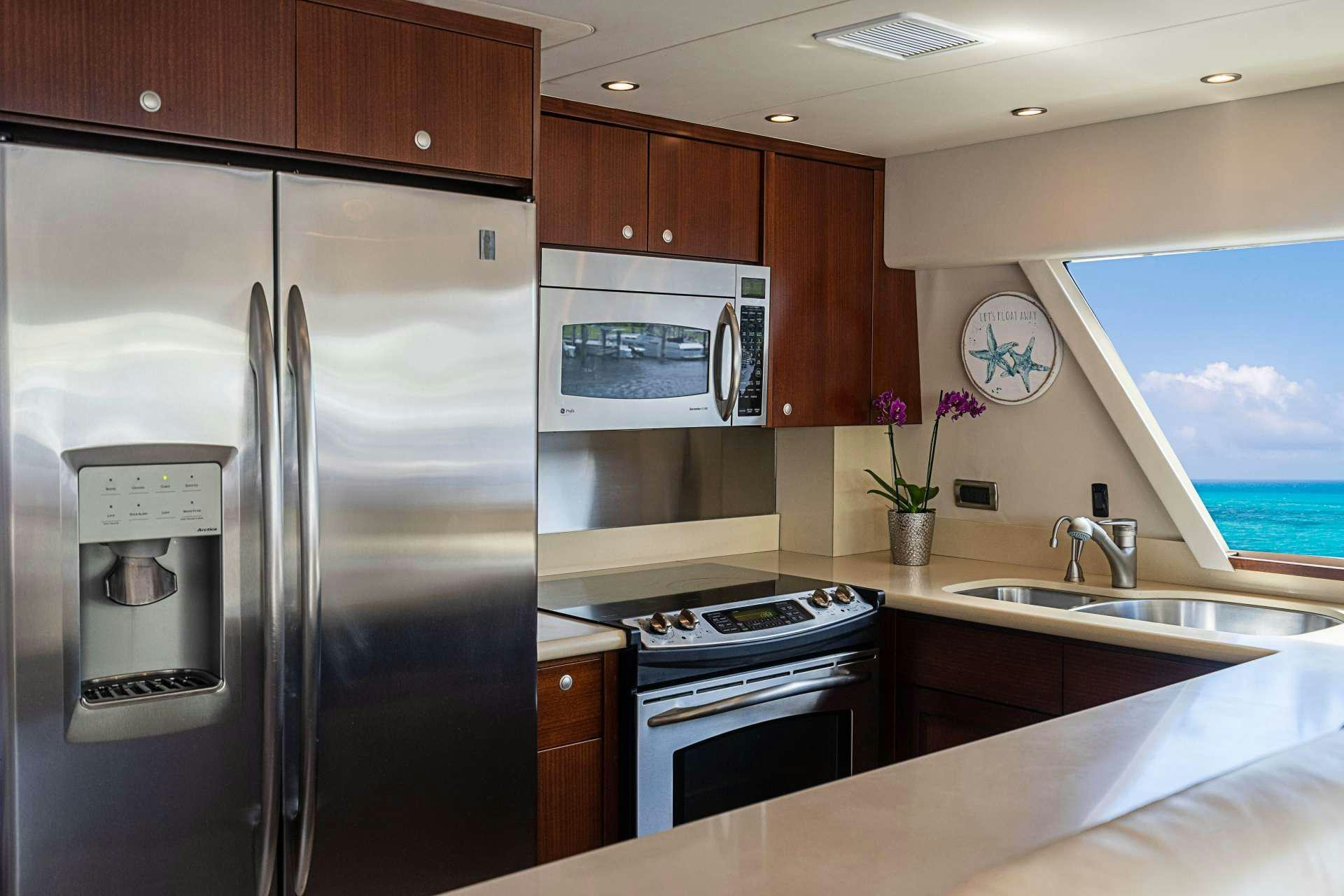 a kitchen with a refrigerator and microwave aboard TRUE NORTH Yacht for Charter